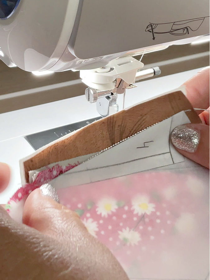 a womans hands holding the piece showing the stitch between pieces 3 and 4