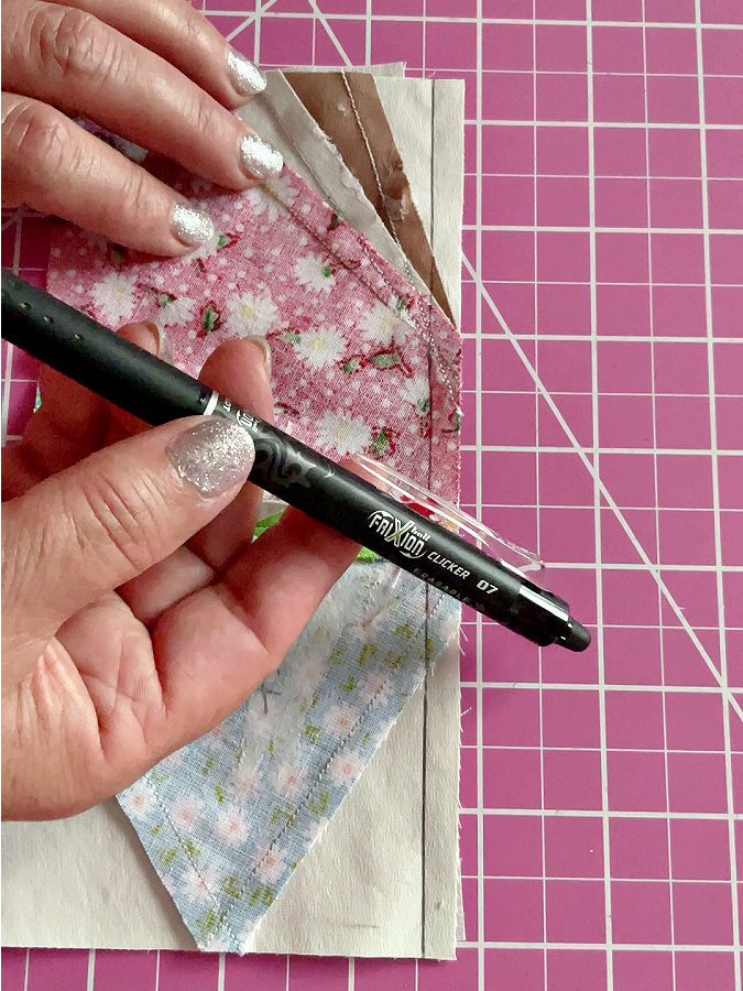 a woman showing the frixion pen used to mark the stitching line butterfly piece in the background