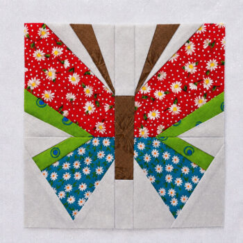 finished butterfly block brown, red, green and blue colors on a light colored background