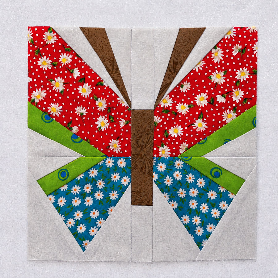 finished butterfly block brown, red, green and blue colors on a light colored background