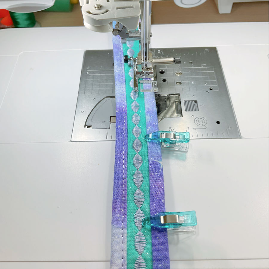 sewing the binding strip to one side of the purse strap the part not sewn yet held in p;lace by clips