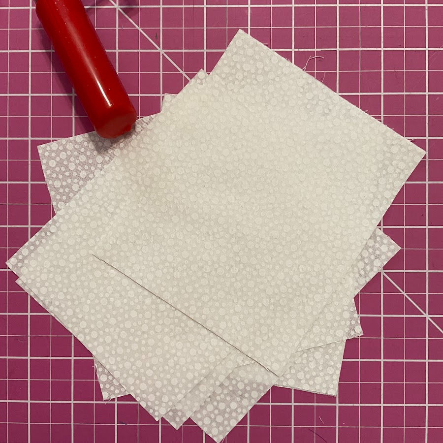 the white fabric rectangles already cut in a stack on the cutting table