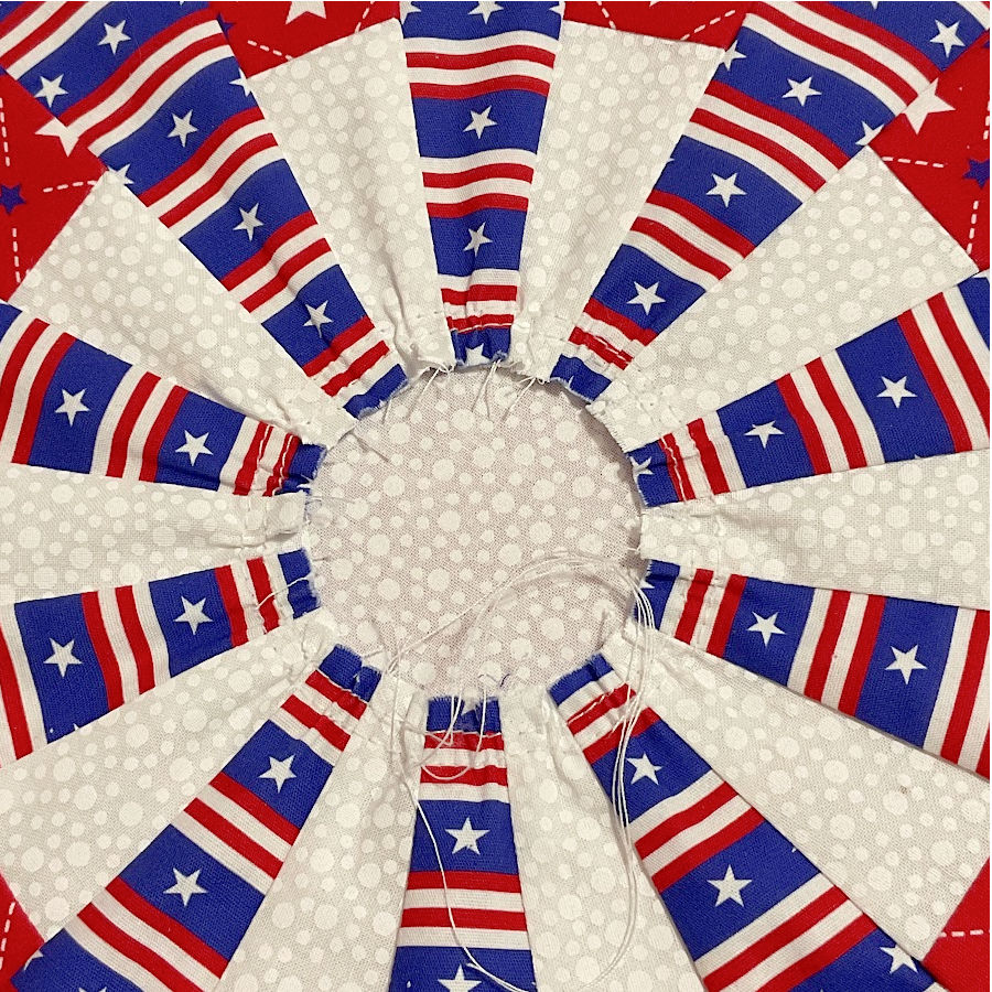 two rows of gathering stitches sewn close to the narrow end of the dresden plates to keep the whole construction flat