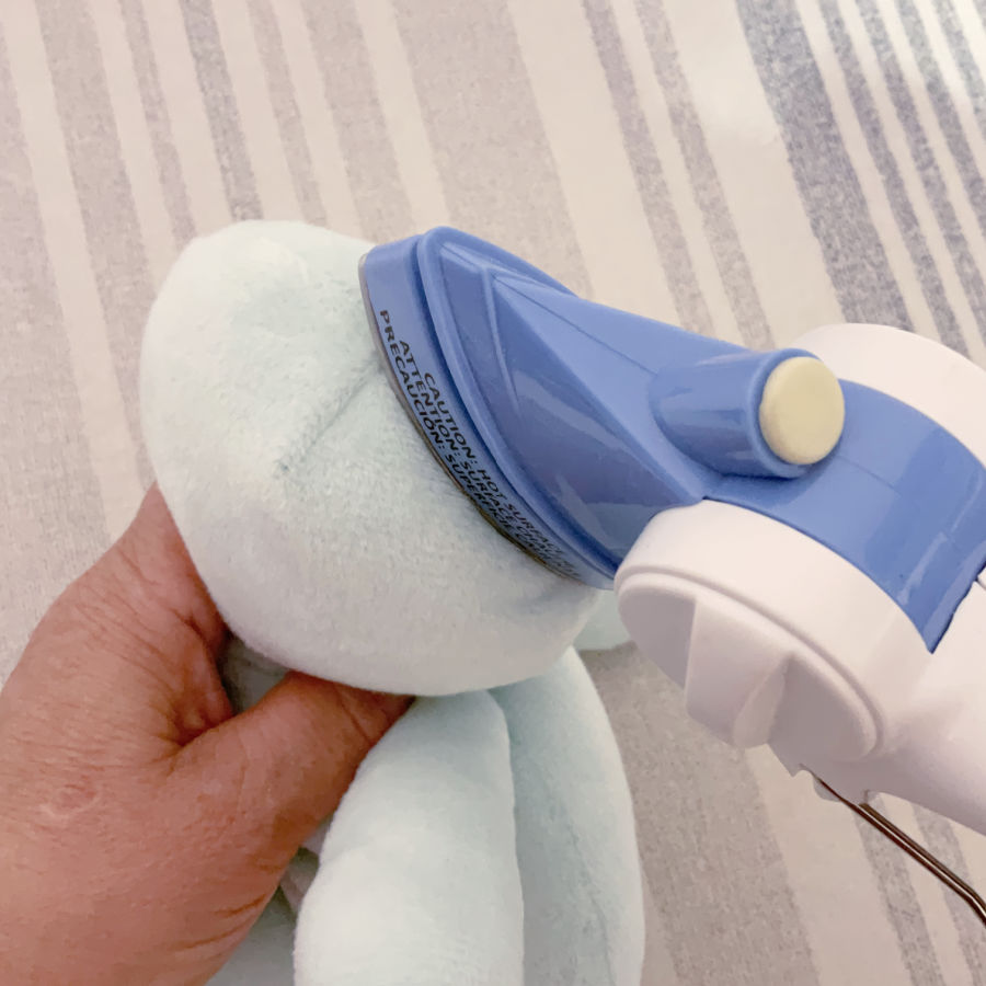 a mini iron while a woman is using it to press the bunny doll