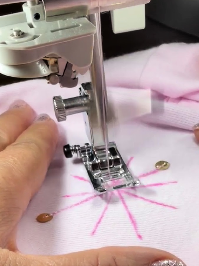 a womans hand holding the material near a sewing machine needle assembly while sewing