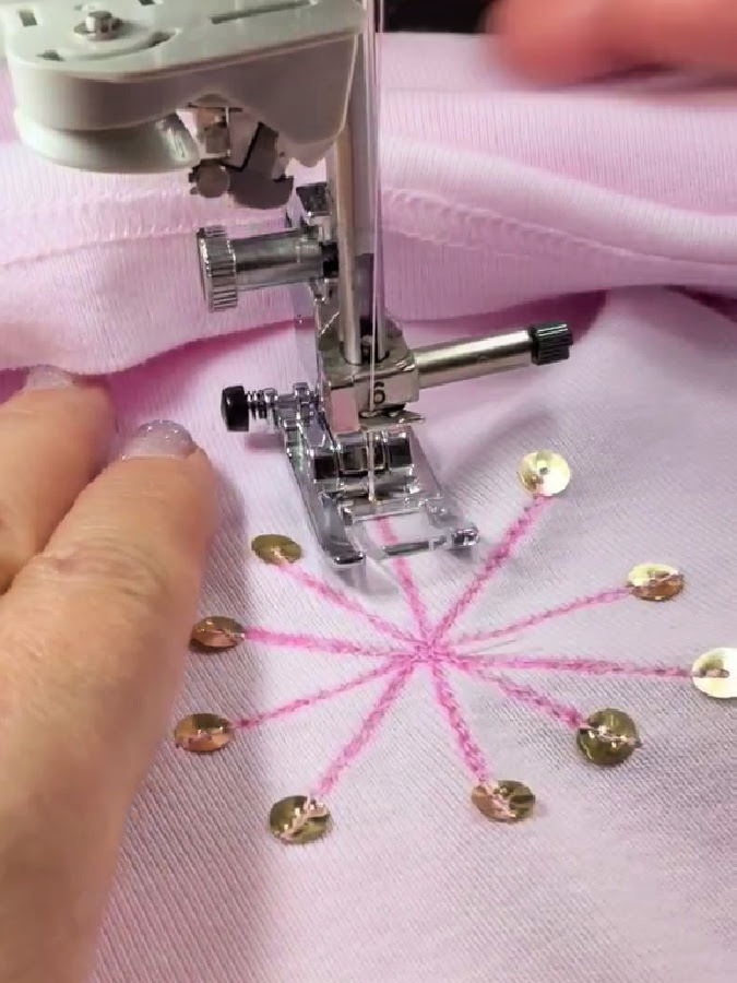 a sewing machine needle assembly shown while sewing the last sequin on the blouse the rest of the ornamental design is complete