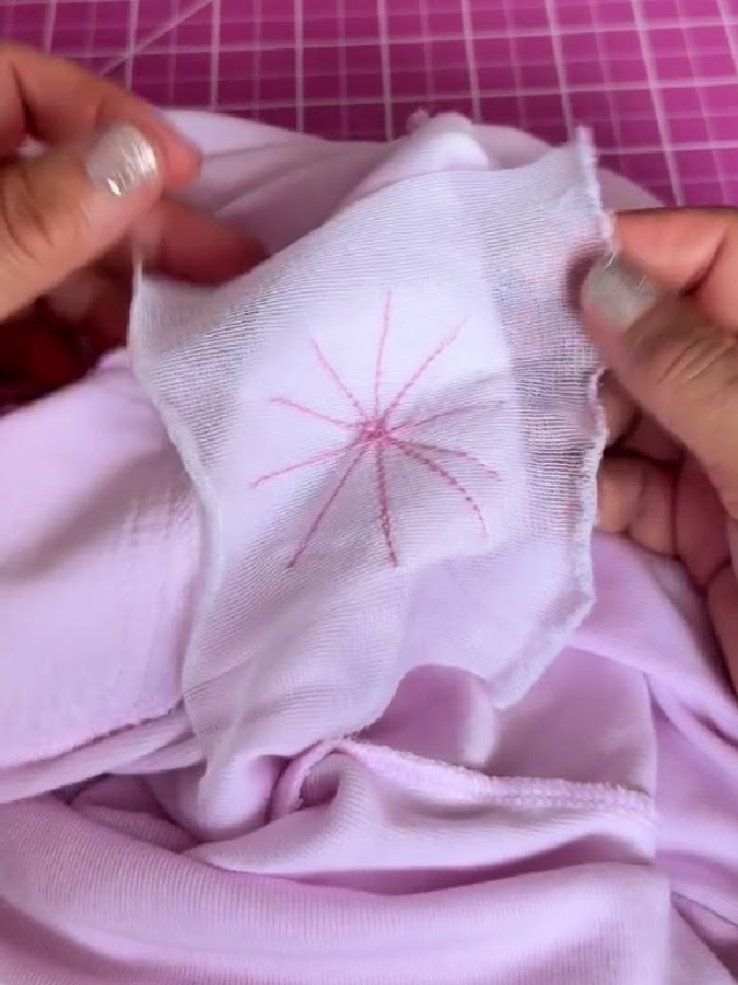 a womans hands shown while removing the stabilizer piece from the back of the blouse