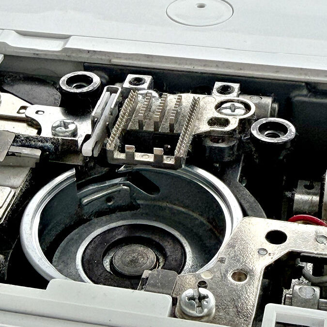 close up of the feed dogs on a sewing machine with lint and dust on them