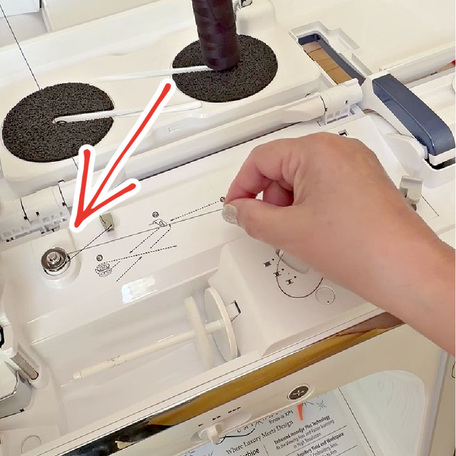 a womans hand shown while threading the bobbin winding mechanism on a sewing machine