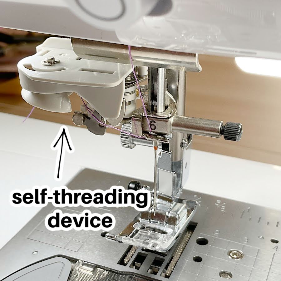 close up of the self threading function of a high end sewing machine the words self threading device in the lower left corner anb arrow points to the actual device