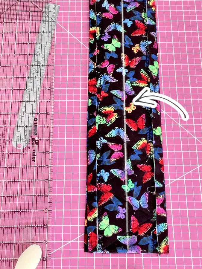 the two parts of the potholder on on top of the other an arrow points to a line drawn through the middle of the material