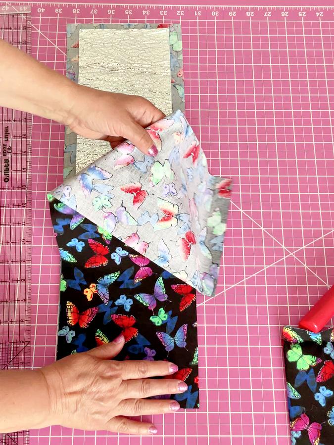 a womans hands folding the piece of the fabric over the heat resistant batting