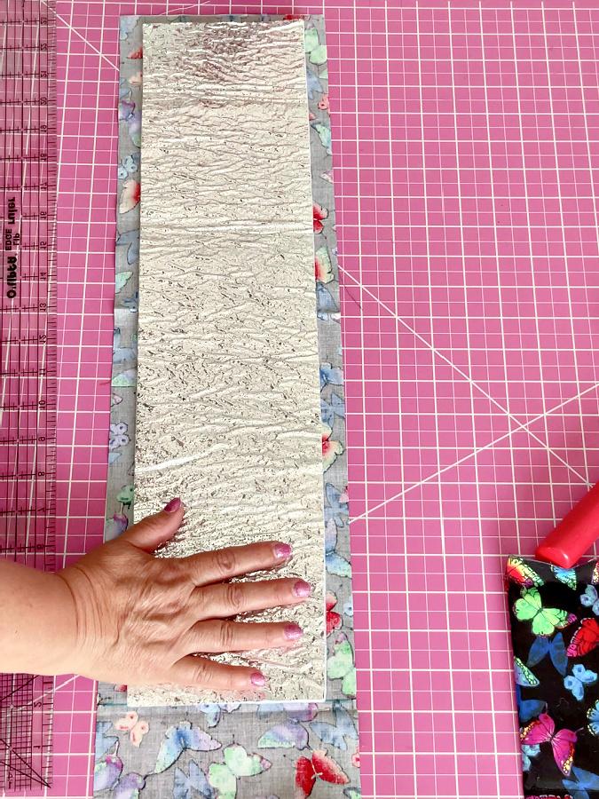 the piece of heat resistant batting placed on the fabric between the marks done previously