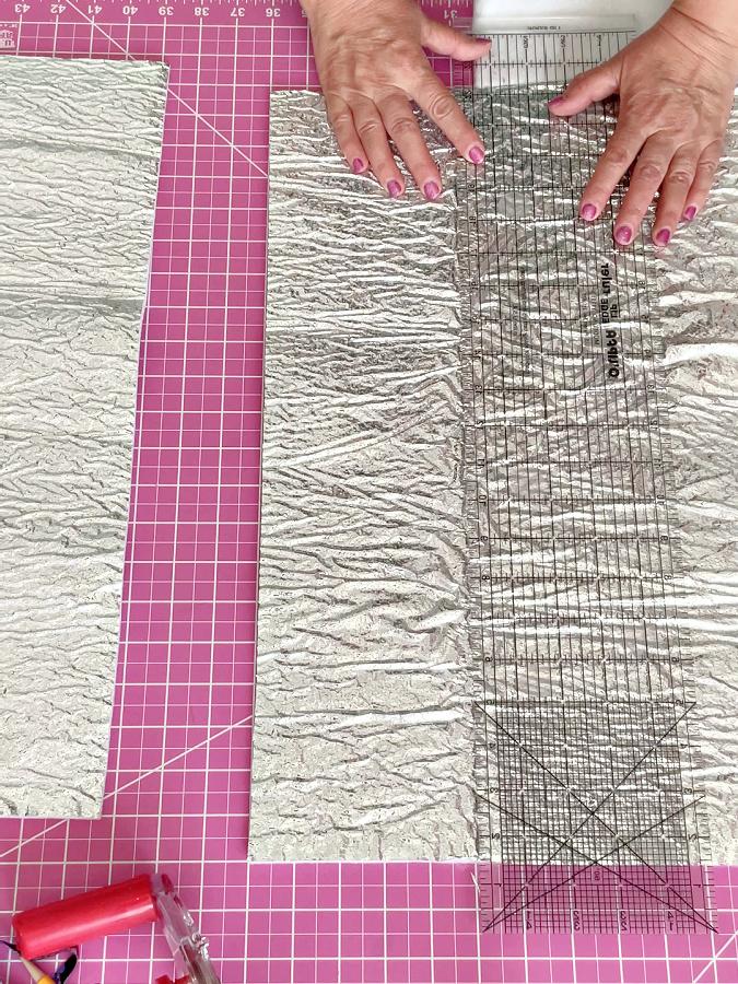 a womans hands hold a ruler on a piece of heat resistant batting