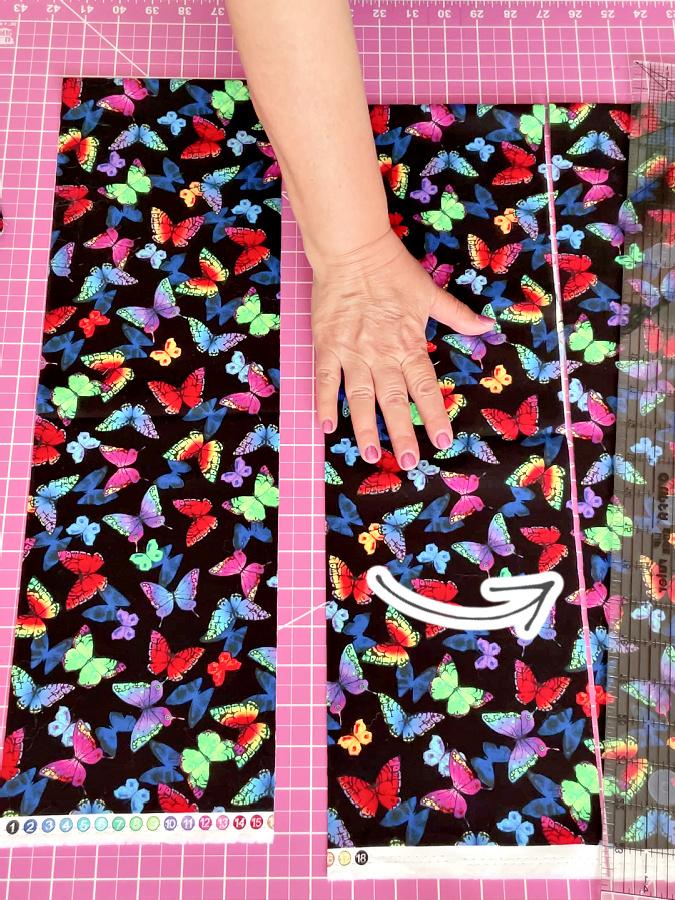 a womans hand holdiung pieces of material on a cutting table an arrow points to the last cut