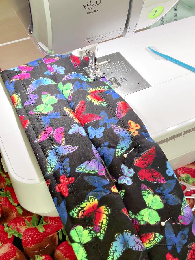 a sewing machine shown while sewing all around the potholder