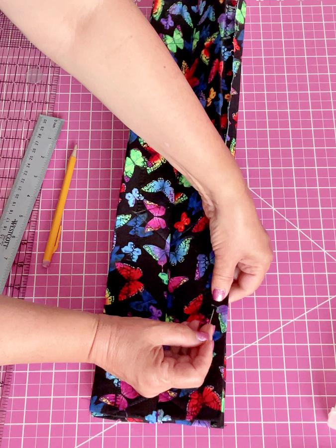 a womans hands shown while folding and pinning the second side of the potholder