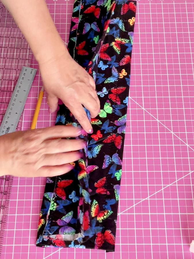 a womans hands shown while folding the potholder from the middle line outwards