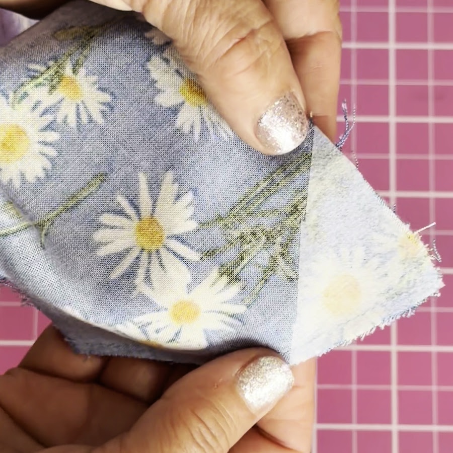 a womans hands hold the fabric with interfacing fused on the damaged corner
