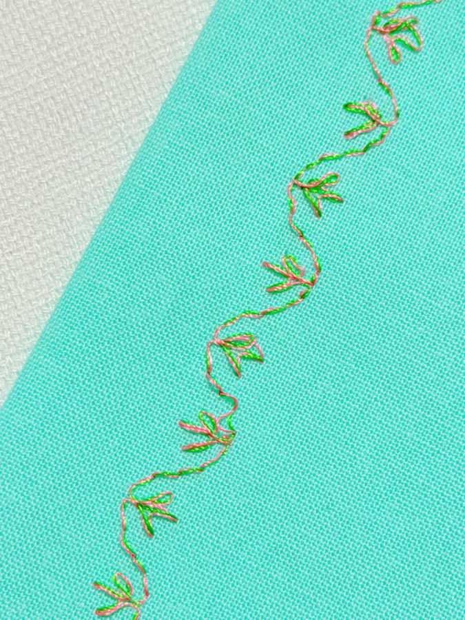 decorative stitch of a vine with leafs sewn with a double eye needle both thread colors show in the stitch