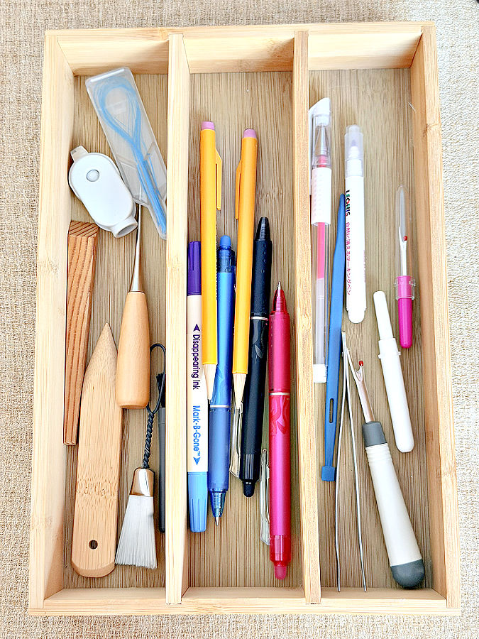 a wooden cutlery tray used to hold and organize sewing tools and marking pens