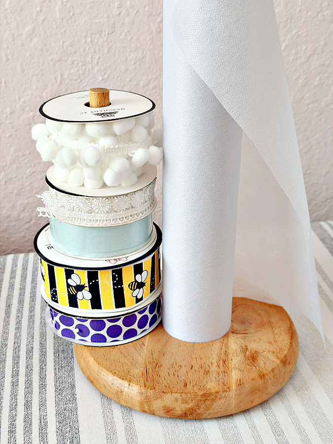 a paper towel holder used to hold a roll of interfacing and some ribbons