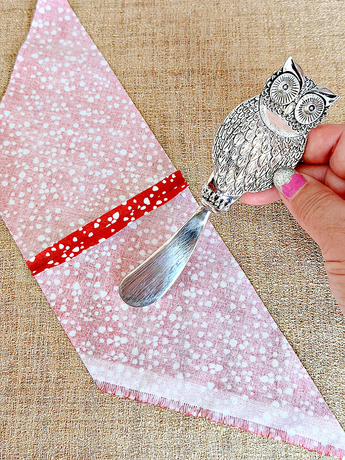 a butter knifw with an owl handle used to smooth a piece of fabric