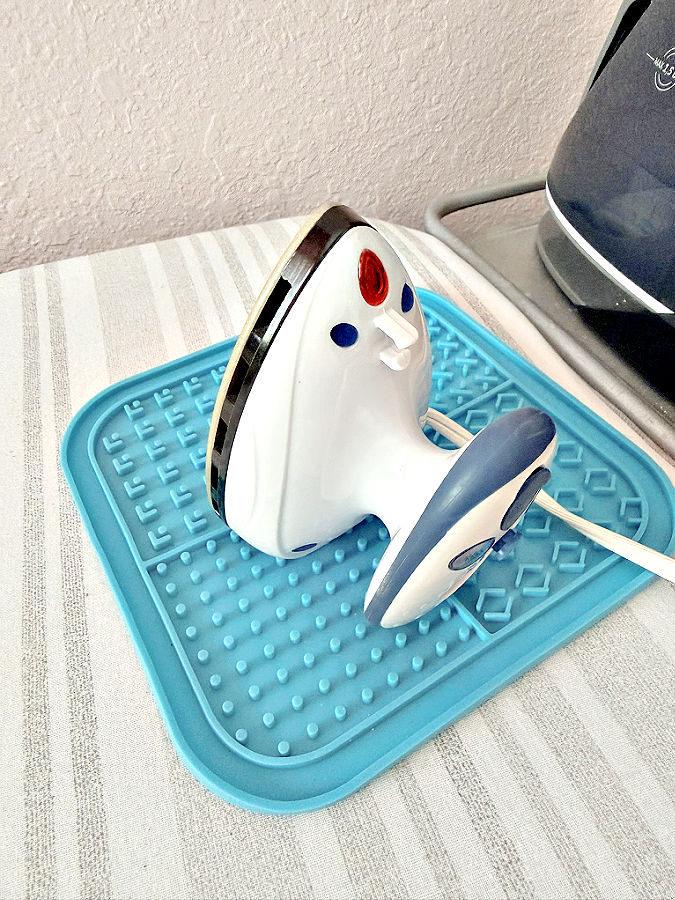 a mini iron sits on a blue silicone trivet