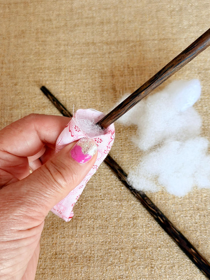 a womans hand holds a small bag a chopstick used to insert stuffing in the bag