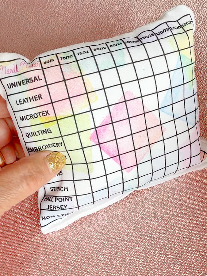 a womans hand holds the needle storage pillow for display