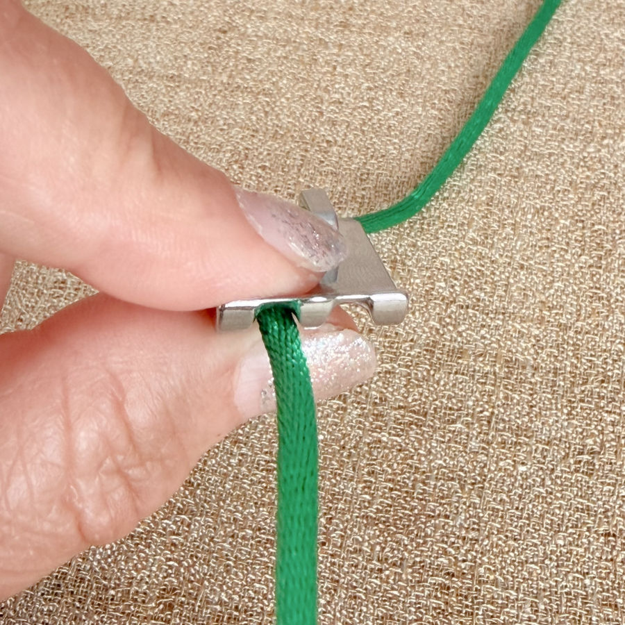 a woman holds between two fingers a cord inside the groove from a piping foot