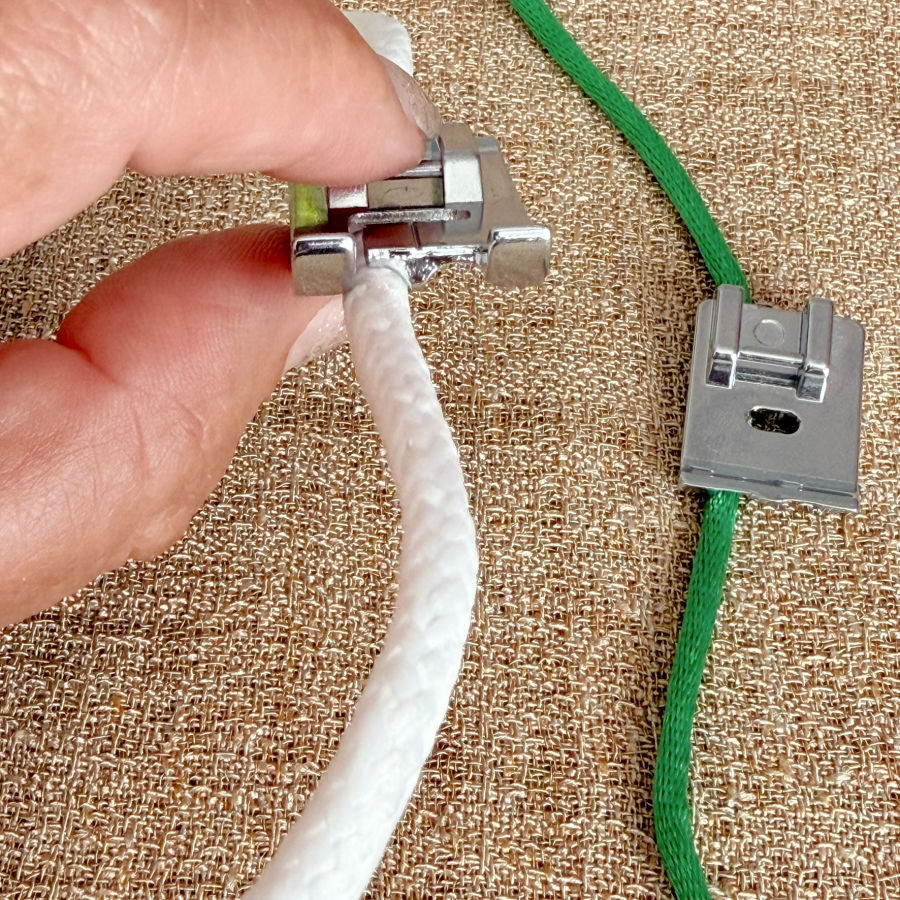 a woman holding a piping foot with a thick cord between two fingers a piping foot with a narrower cord in the background