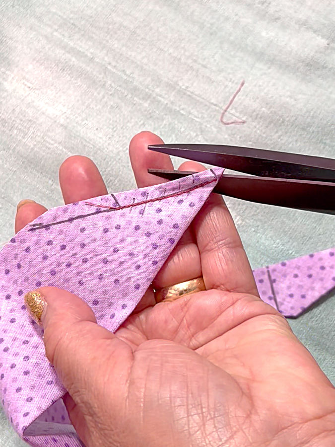 a woman holds a pair of scissors while cutting the excess fabric