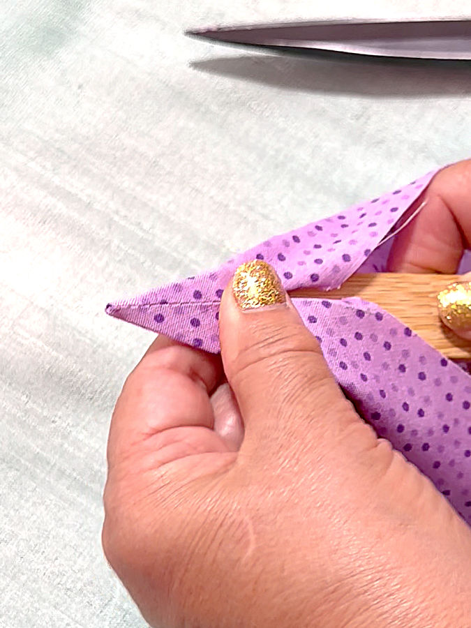 a woman using a wooden point turner to turn the corner of the fabric