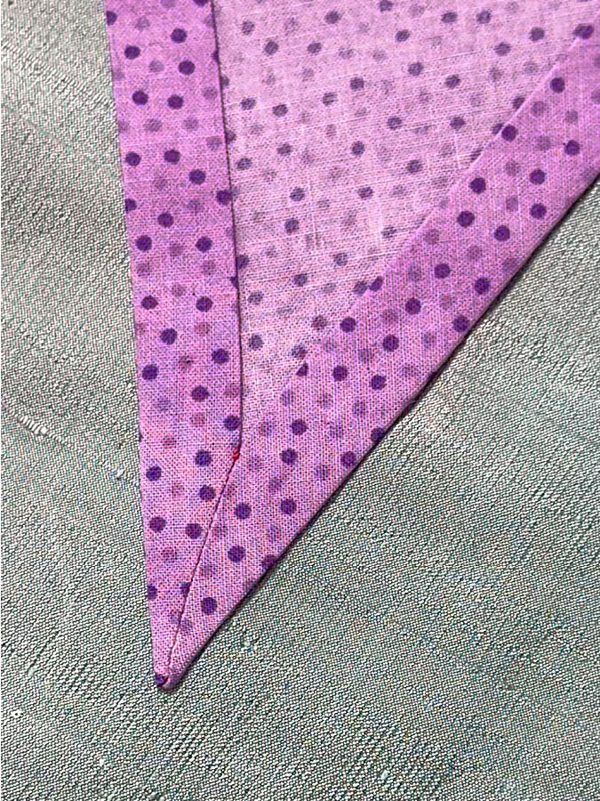 the fabric with the corner seen from the wrong side after pressing