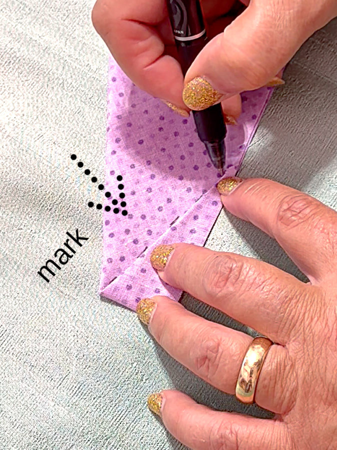 a woman marks the line created by the fold and arrow and the word mark point to the line to be marked