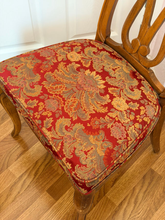an upholstered dining room chair the cushion has piping all around