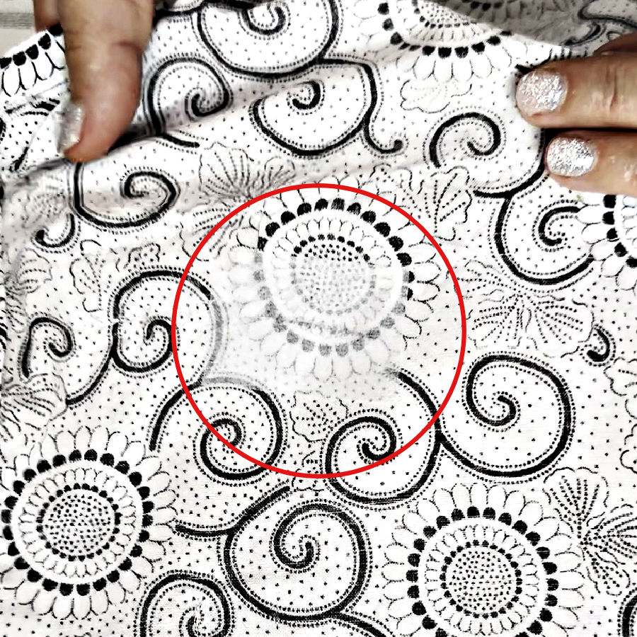 a womans hands show the piece of fabric with the area in which interfacing has been applied in a red circle