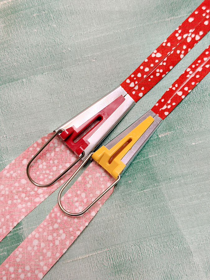two bias tape makers with each with a strip of fabric inserted