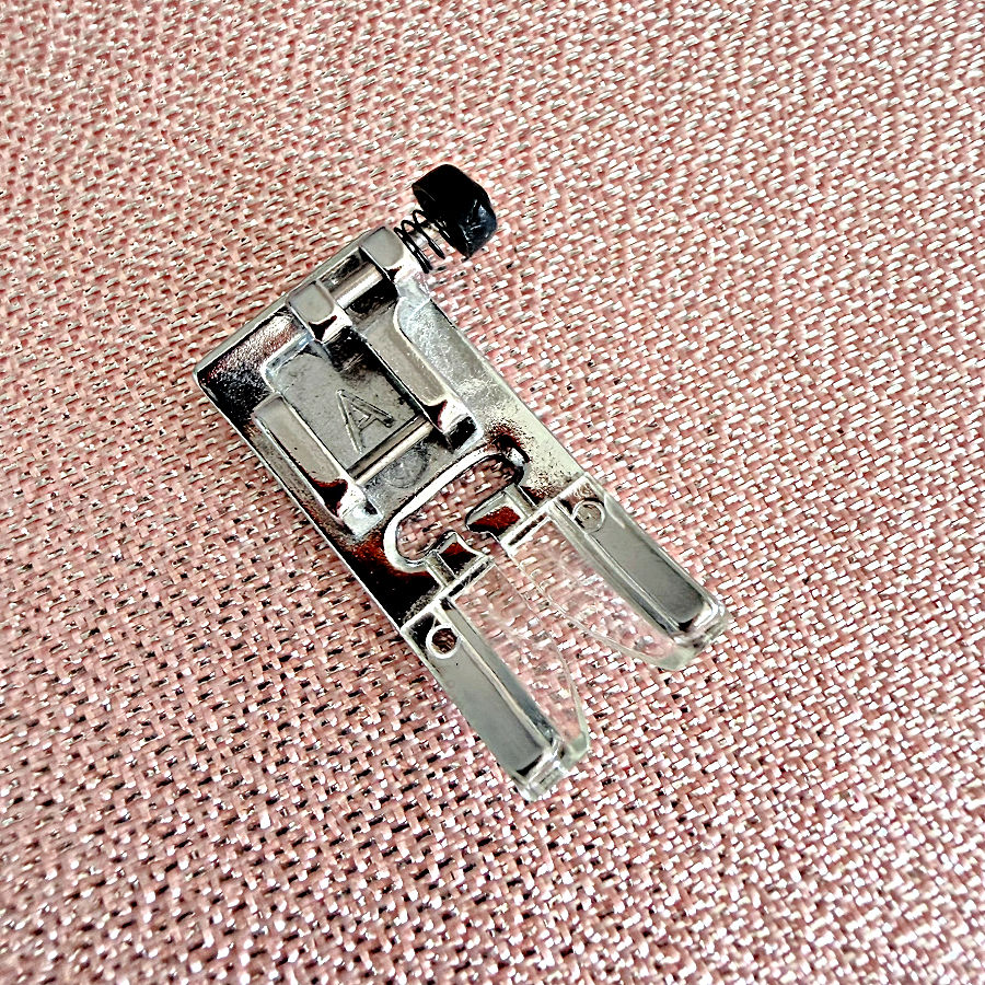 closeup of the sewing machine presser foot A with a black button visible