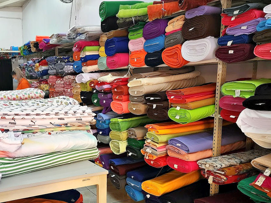 fabric bolts of various colors in a fabric store on a shelf and on a table
