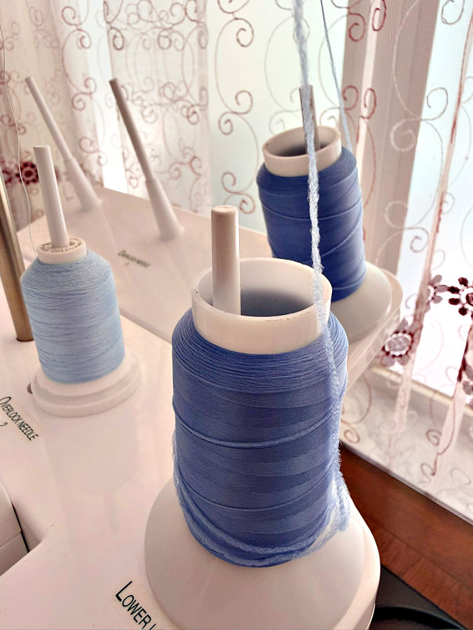 spools of wooly nylon thread mounted on a thread stand on a serger