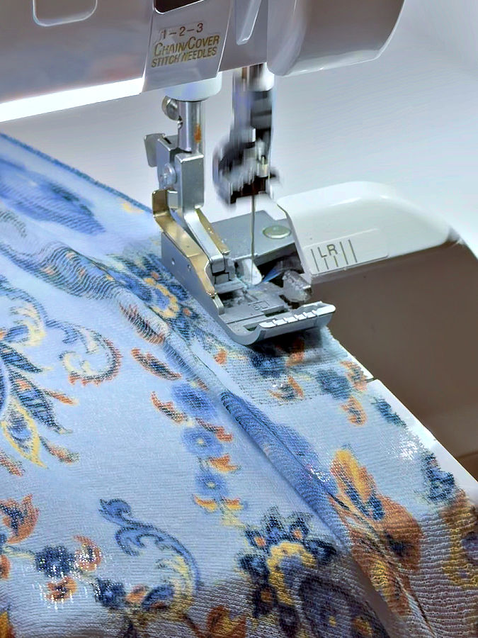 a serger needle assembly while serging the lettuce hem the material in front of the needle visibly stretched
