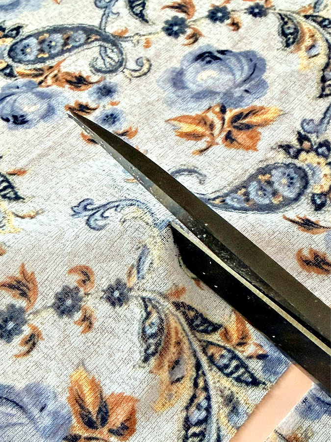a pair of scissors while cutting a piece of fabric