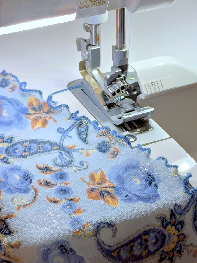 a closeup of the lettuce hem edge in front of a serger needle assembly