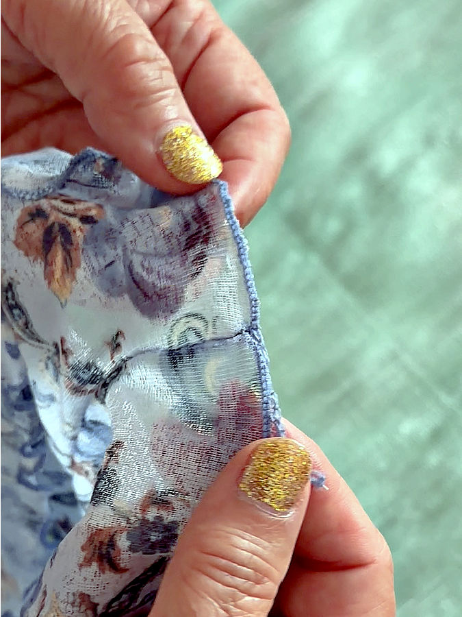 a woman holds for inspection the end of the stitch where the two lettuce hems meet