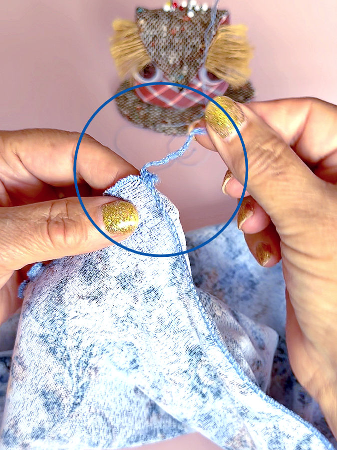 a woman showing the serger tails left after sewing the fabric