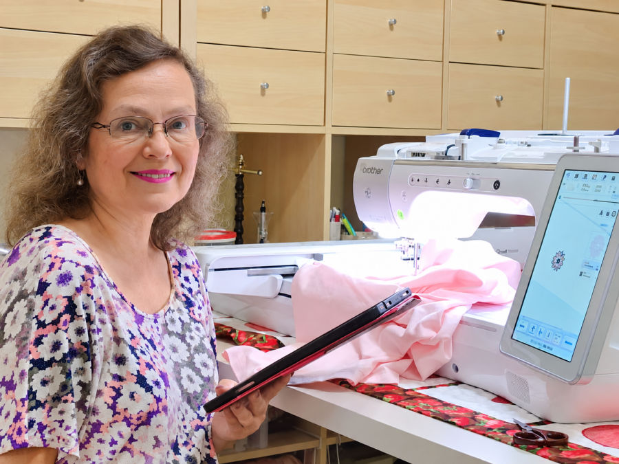 a woman sitting in front of a sewing machine with a tablet in her hands