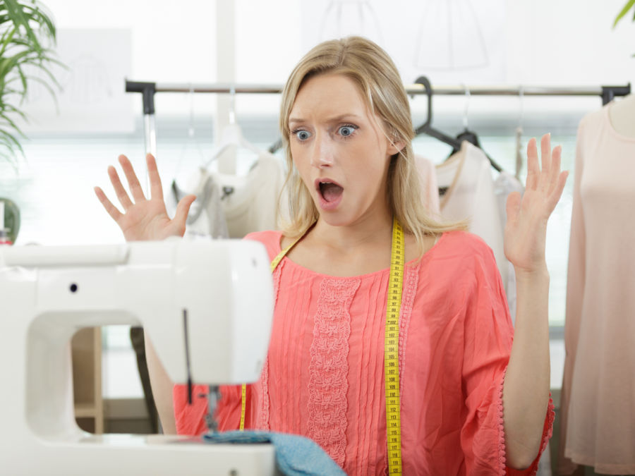a woman shows surprise in front of a sewing machine