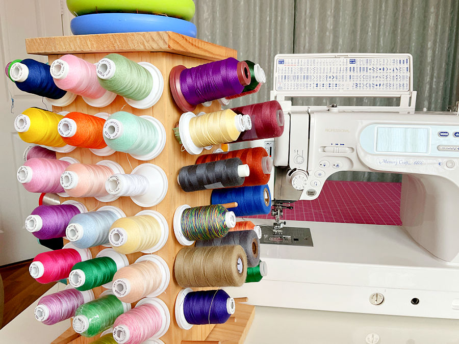 thread spools arranged in a thread stand a sewing machine in the background